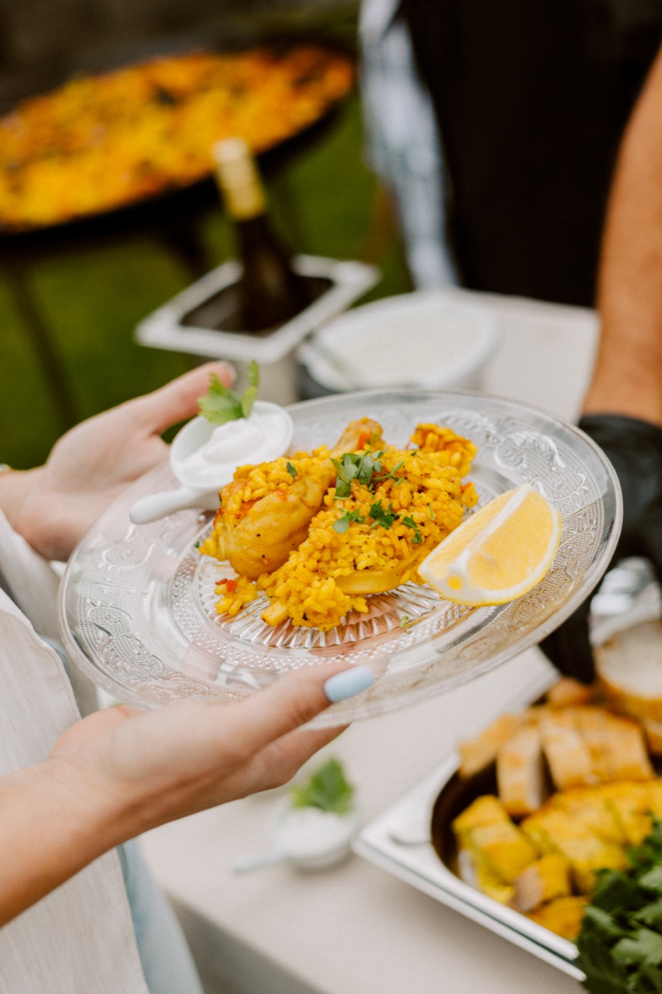 Paella mit Garnele, Muscheln und Zitrone, elegant auf einem Glasteller angerichtet