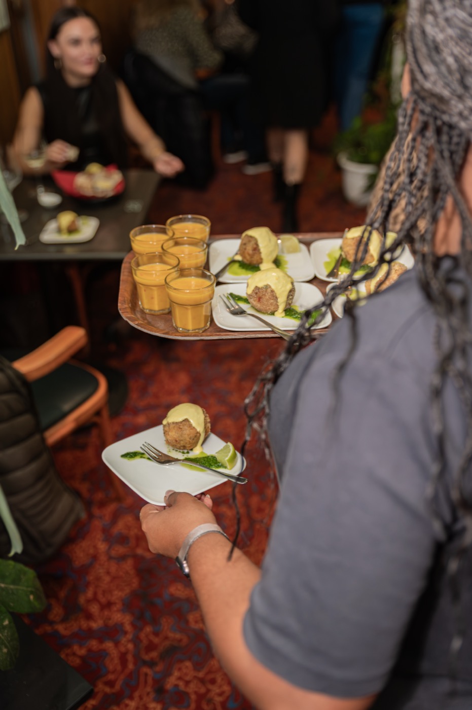 Servicekraft trägt ein Tablett mit Häppchen zu den Gästen