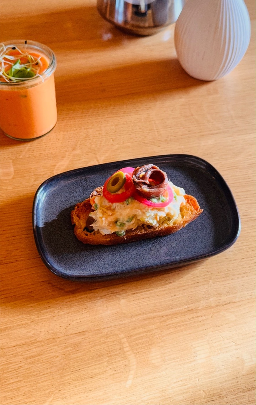 Crostini mit Fischcreme, Oliven, roten Zwiebelringen und Sardelle